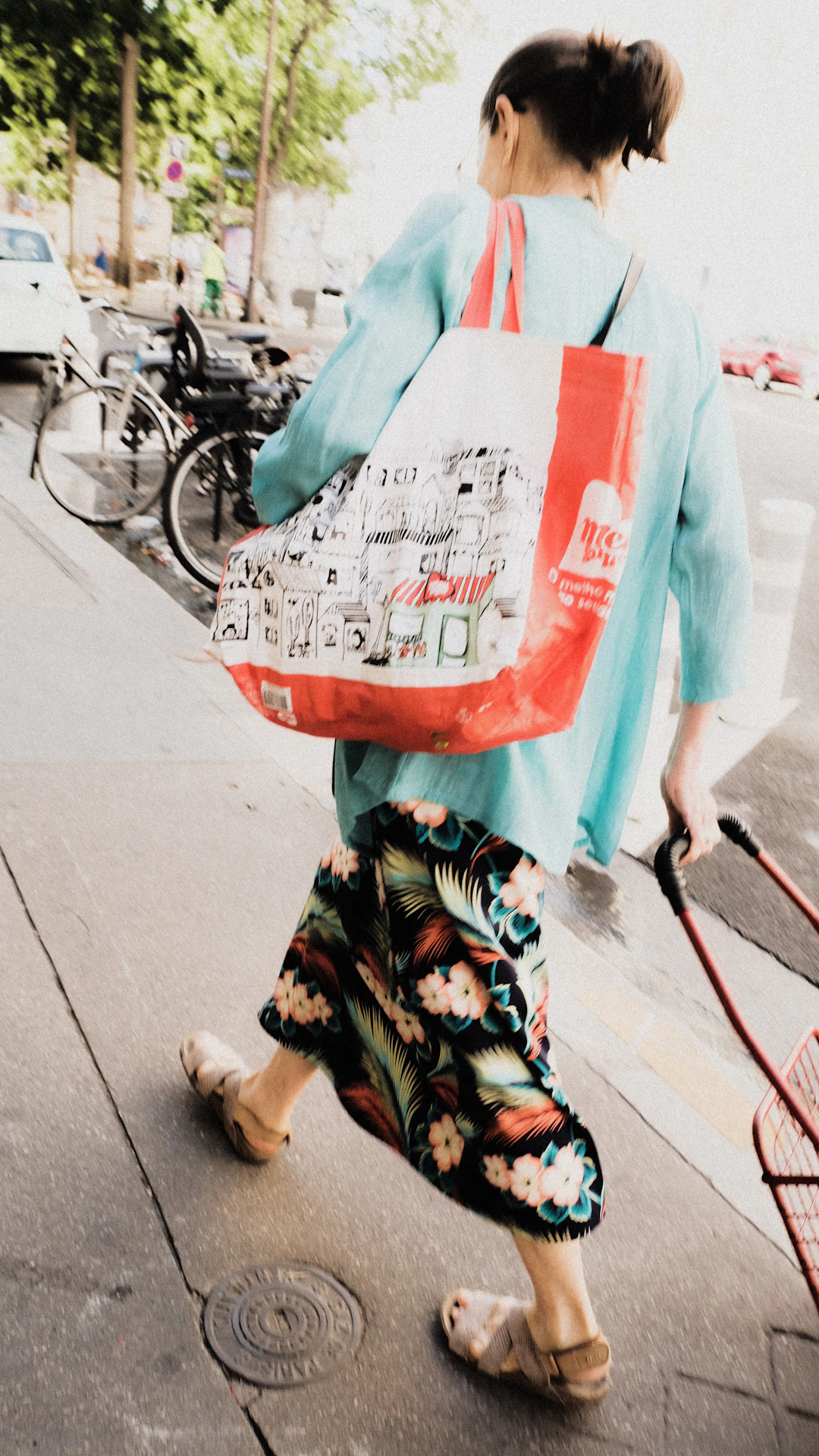 a person walking down a sidewalk carrying a newspaper