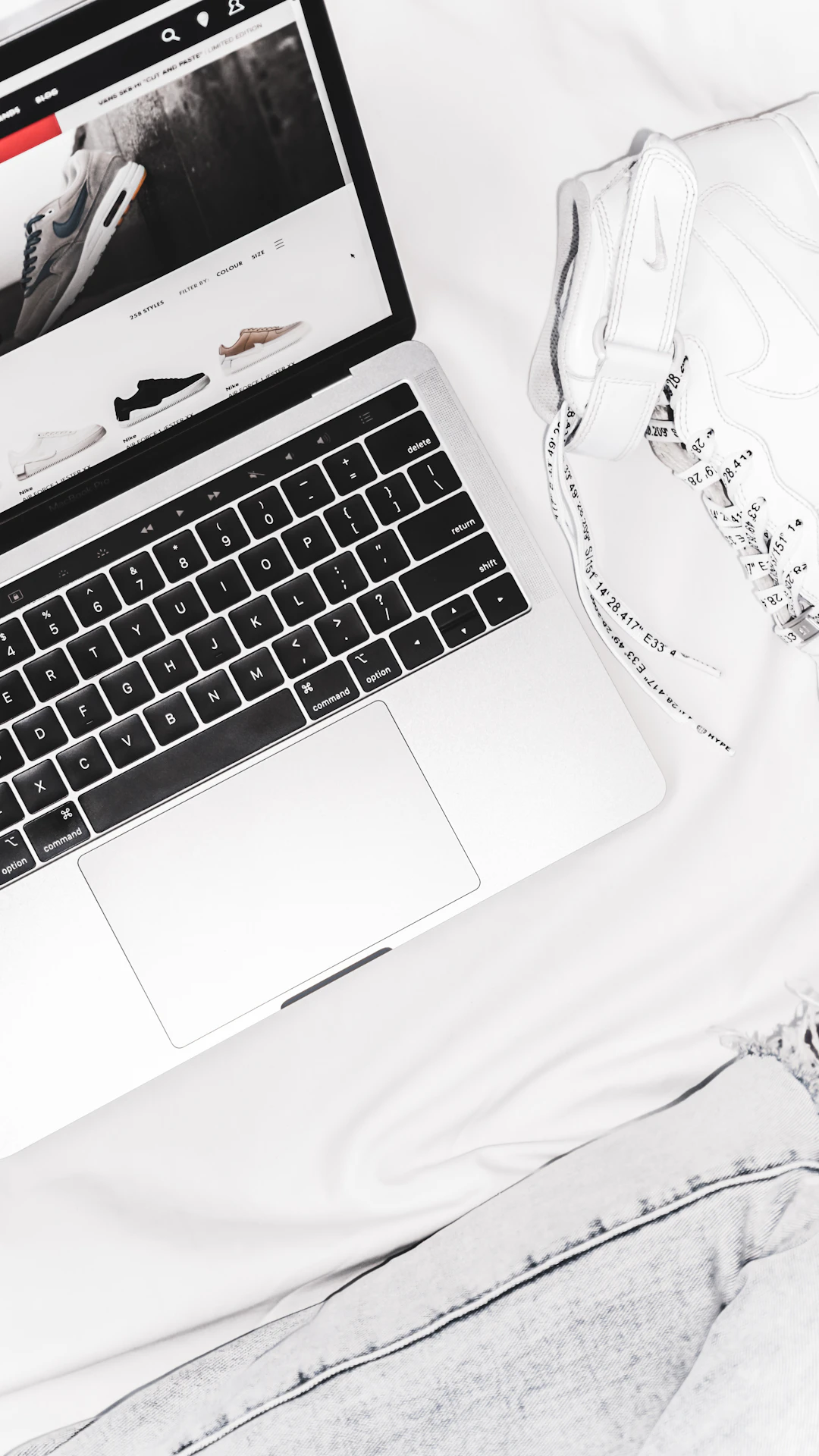 black and white laptop computer near pair of white high-top sneakers