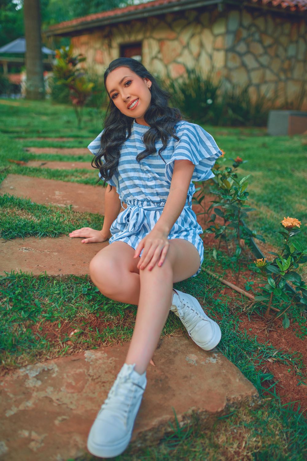 Portrait of a smiling young woman sitting outdoors in a garden in Paraguay.