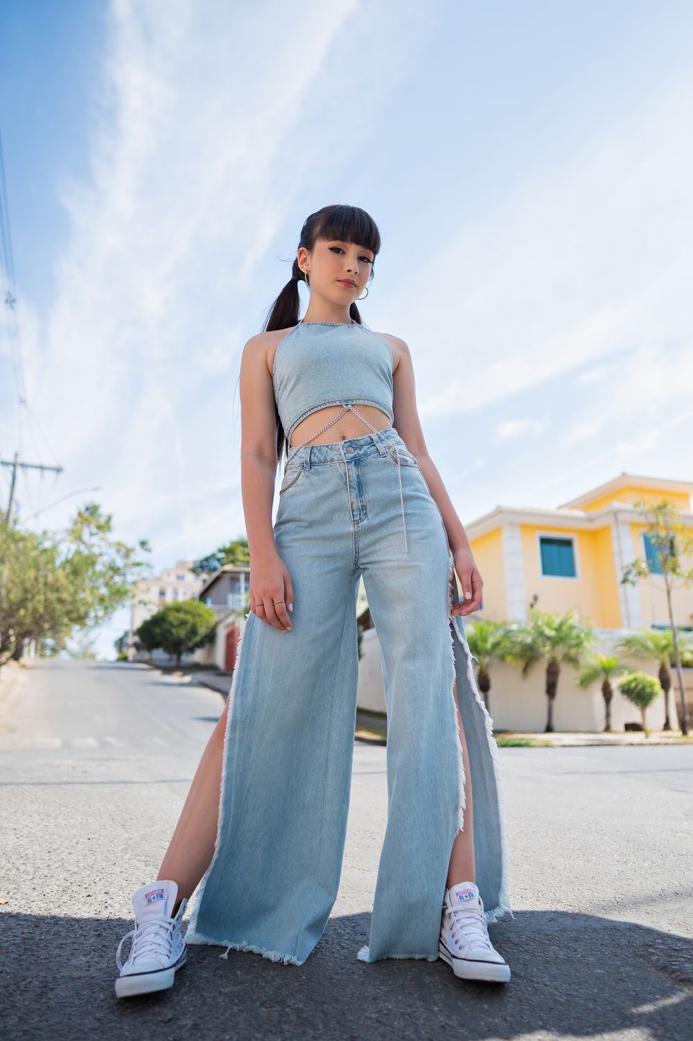 Young woman in trendy outfit posing confidently on a sunny urban street.