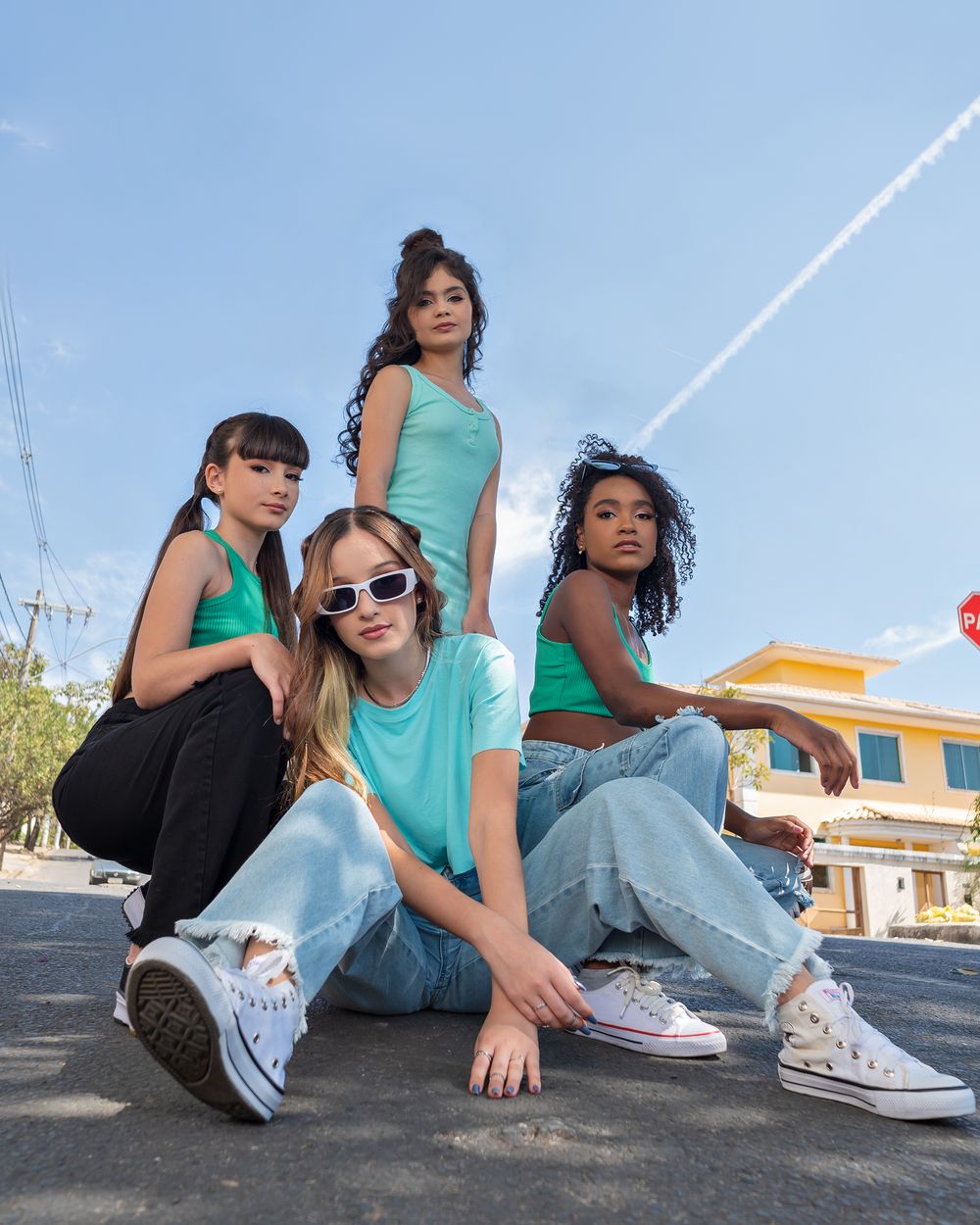 Group of diverse teenage girls in casual fashion posing confidently on city street.