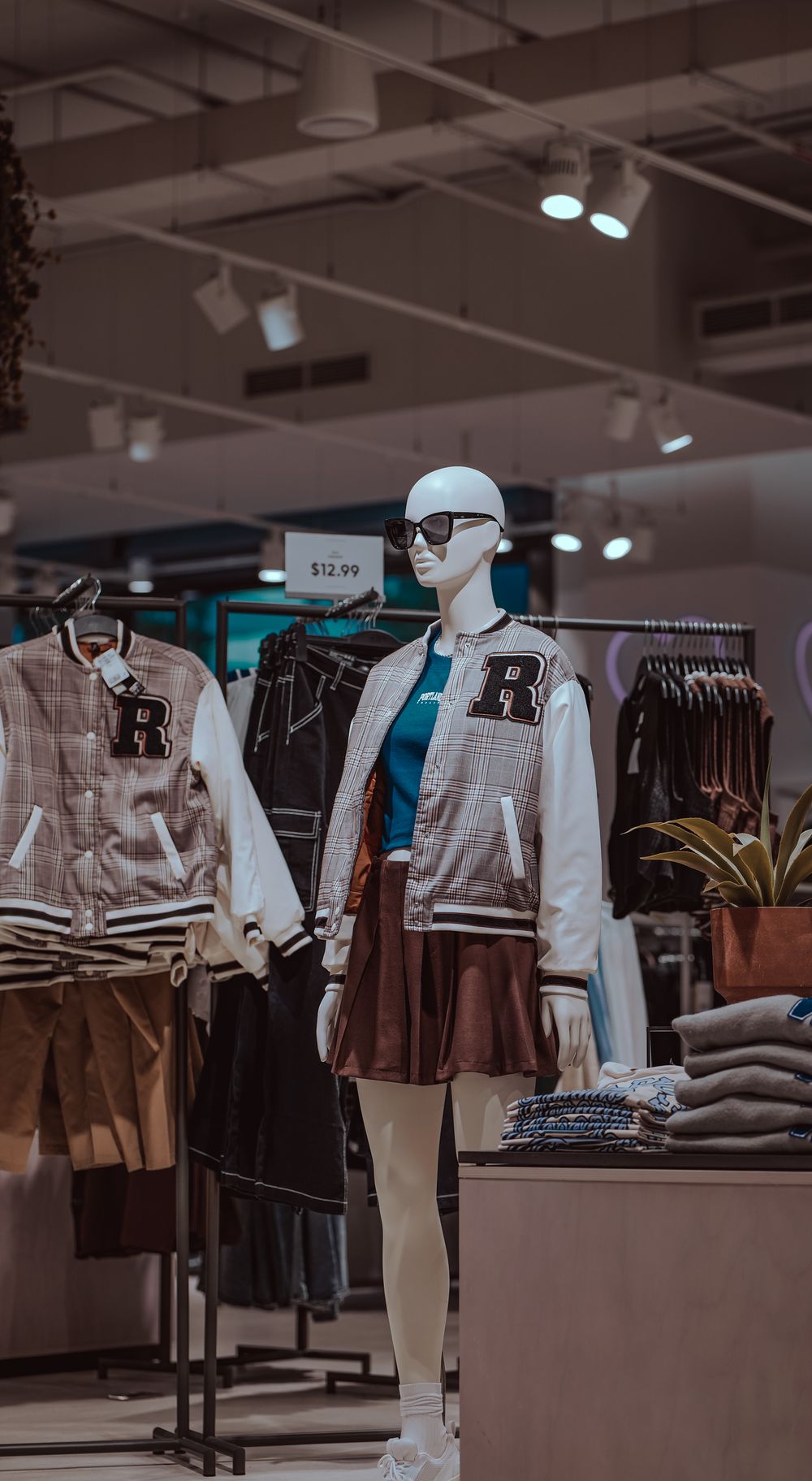 Urban clothing store mannequin showcasing trendy varsity jacket and skirt ensemble.
