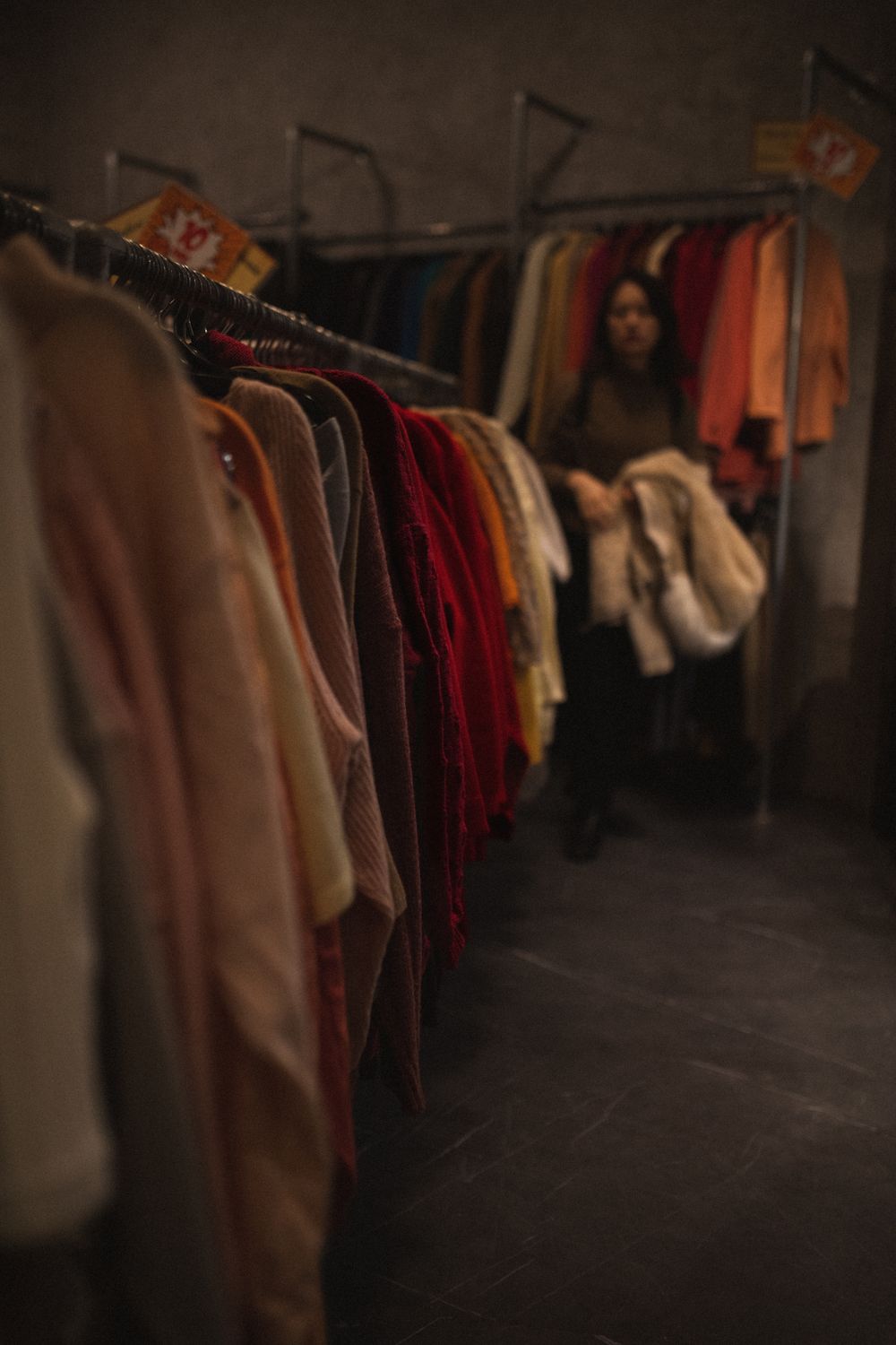 Dimly lit clothing store with a woman shopping in Milan, Italy. Cozy and fashion-focused atmosphere.