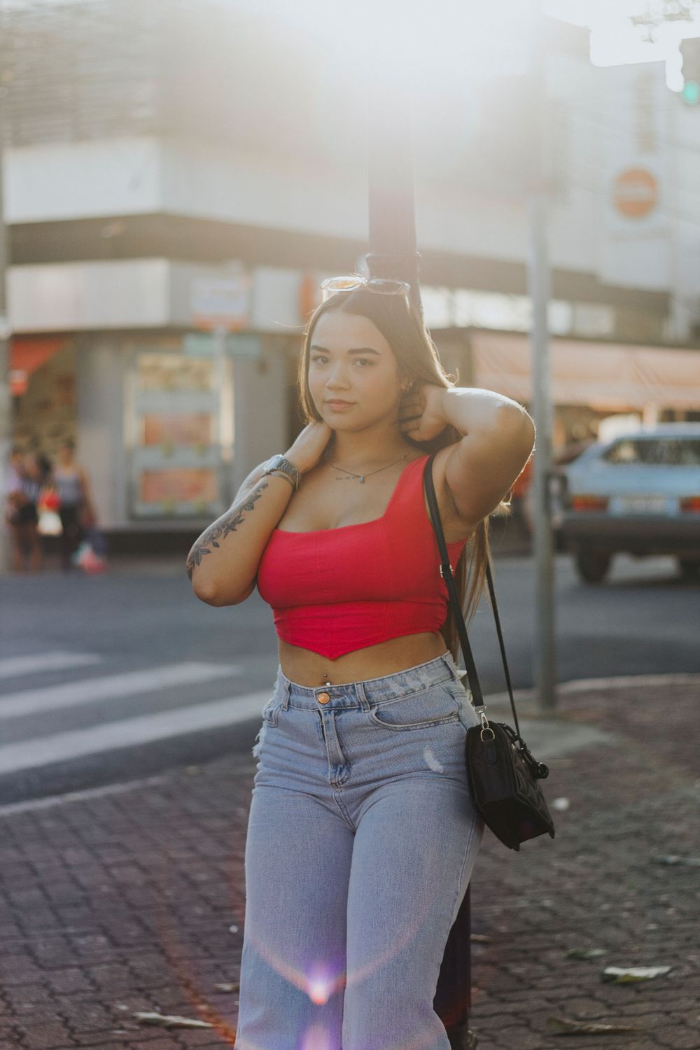 Stylish young woman in red top posing confidently in an urban street setting, embodying city life.