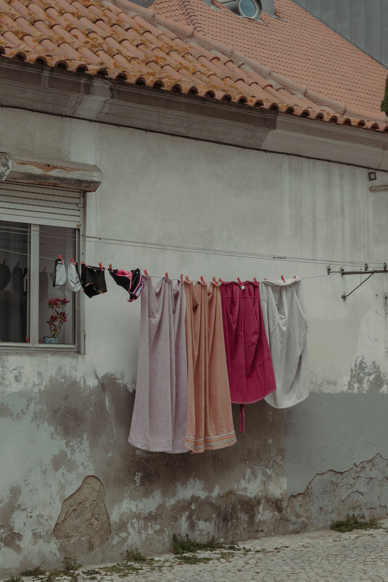 Vibrant clothes and towels hanging on an outdoor clothesline against a rustic wall.