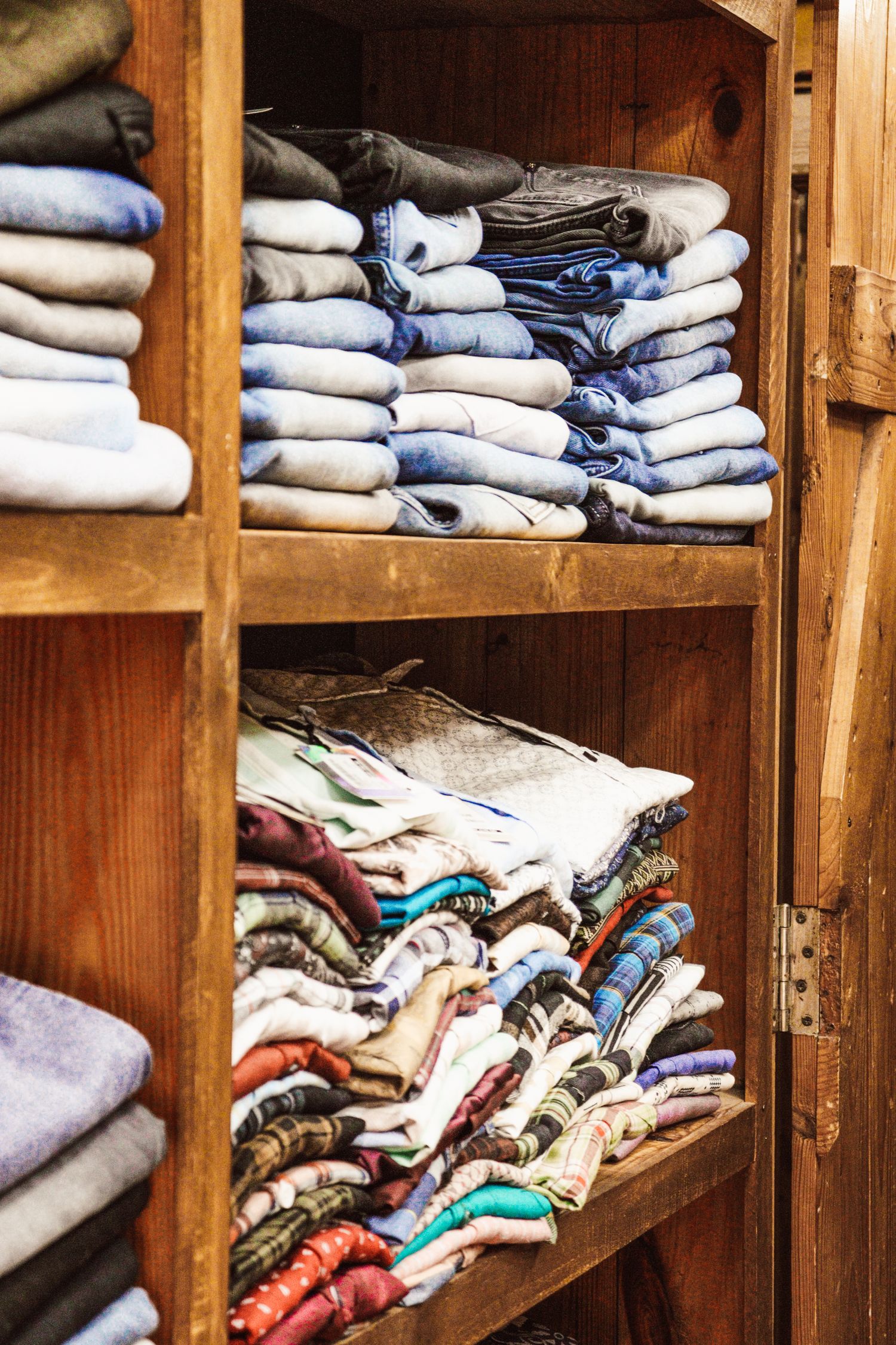 Neatly folded clothes on wooden shelves, showcasing diverse colors and fabric textures.