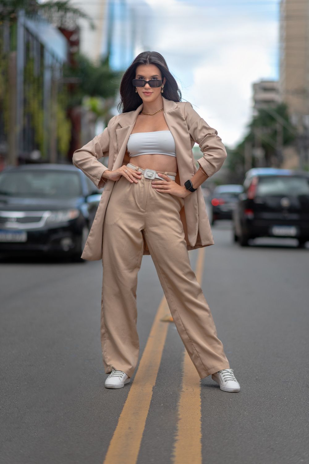 Confident woman in beige outfit posing on urban Nova Lima street.