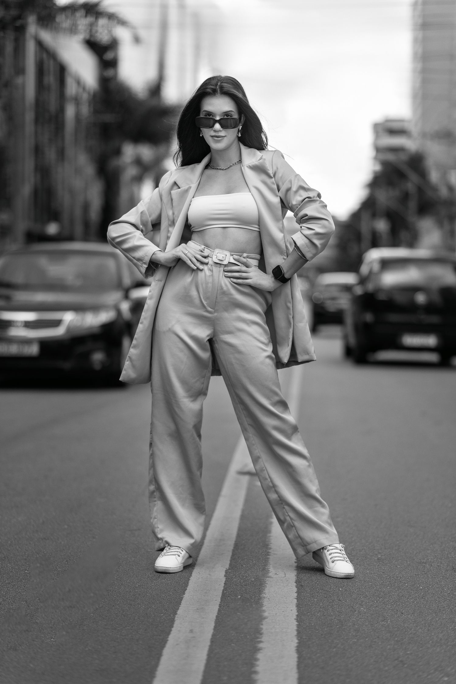 Black and white photo of a stylish woman posing confidently in urban streets of Belo Horizonte, Brazil.