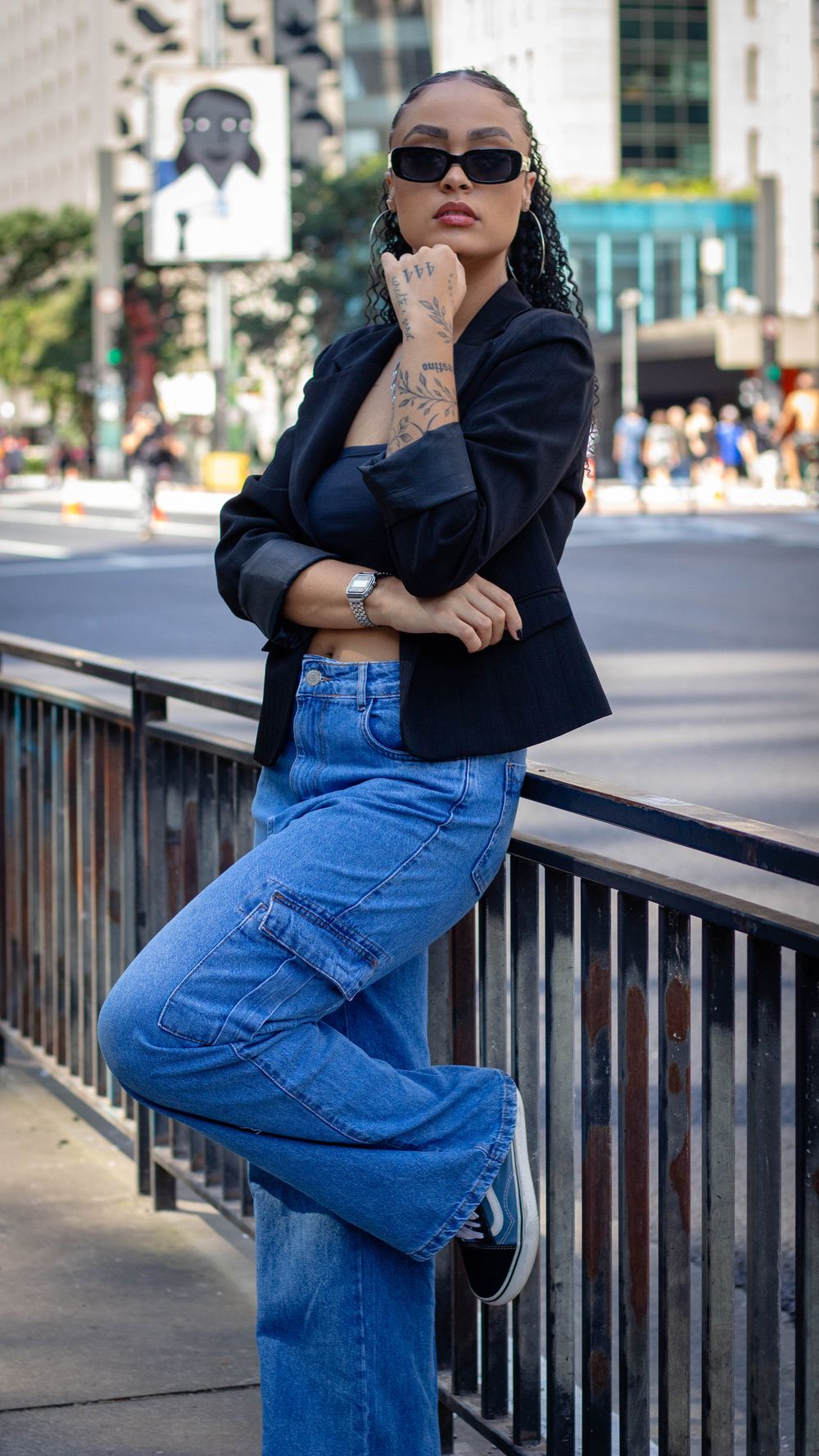 Stylish woman in denim and sunglasses poses in urban setting. Fashion-forward street style.