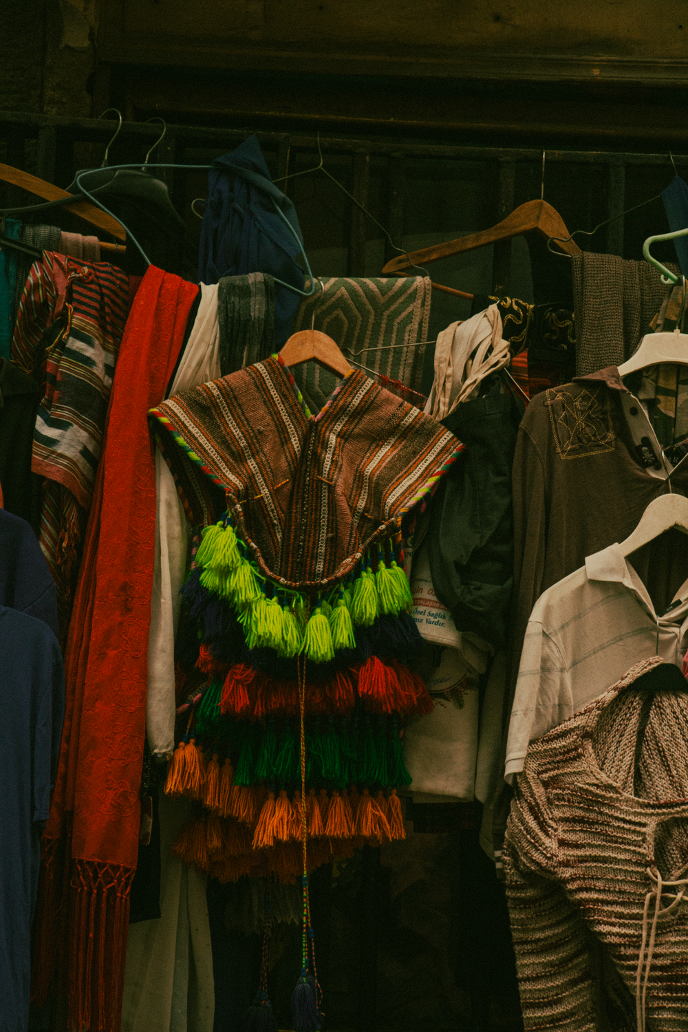 Assorted colorful ethnic clothing displayed on hangers in a dimly lit setting, showcasing traditional designs.