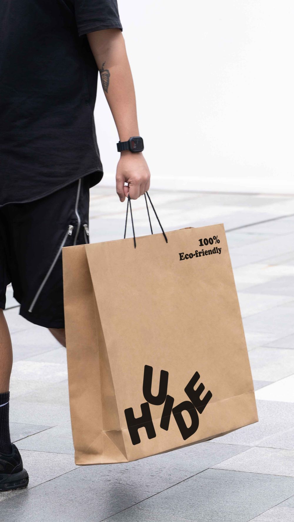 Person carrying eco-friendly kraft paper bags on a city street demonstrating sustainable shopping.