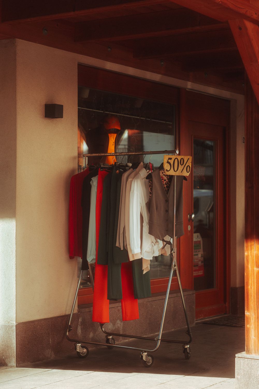 Outdoor clothing rack with assorted fashion garments on sale, marked 50% off.