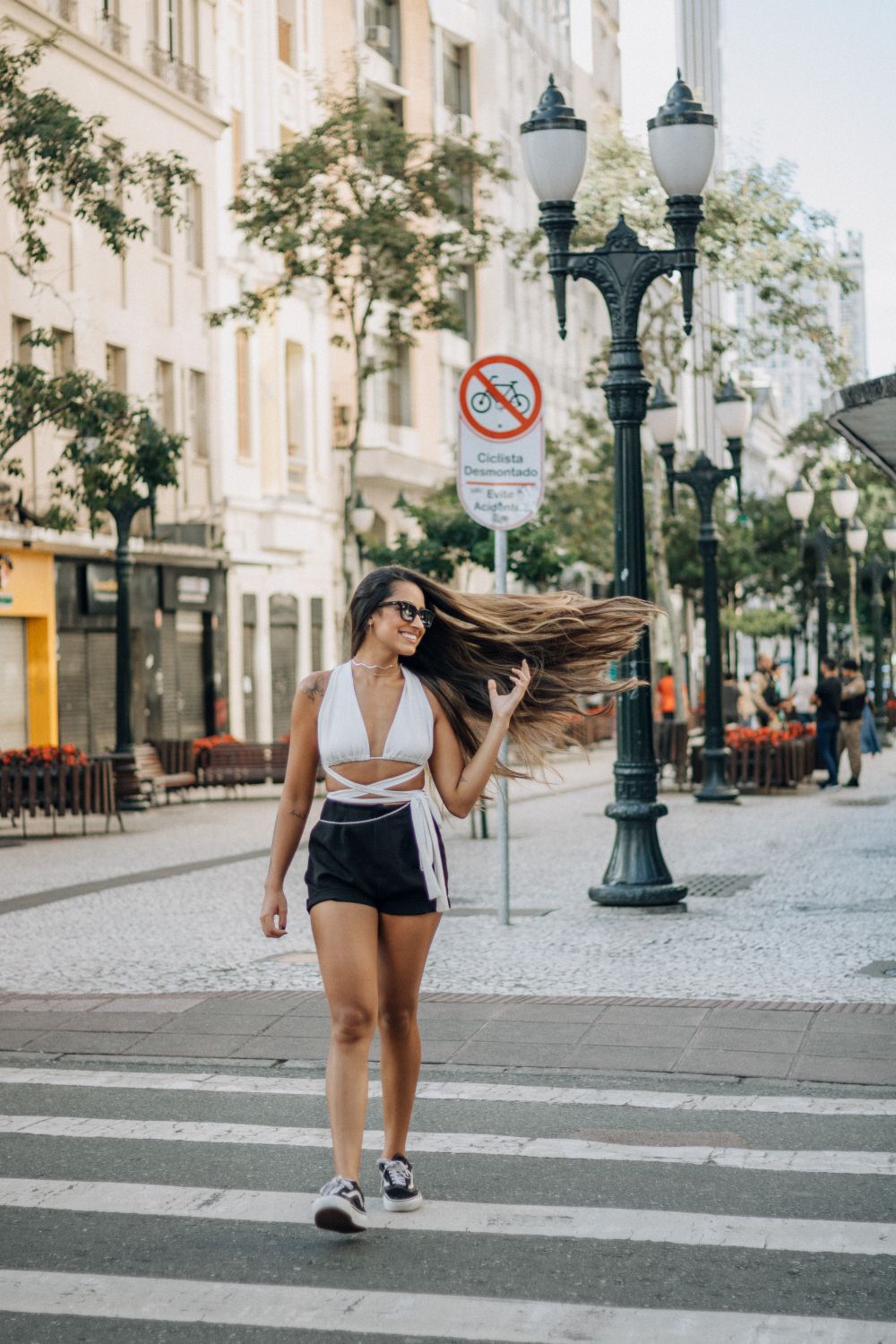 Stylish young woman confidently walking in urban environment, long hair flowing in the breeze.