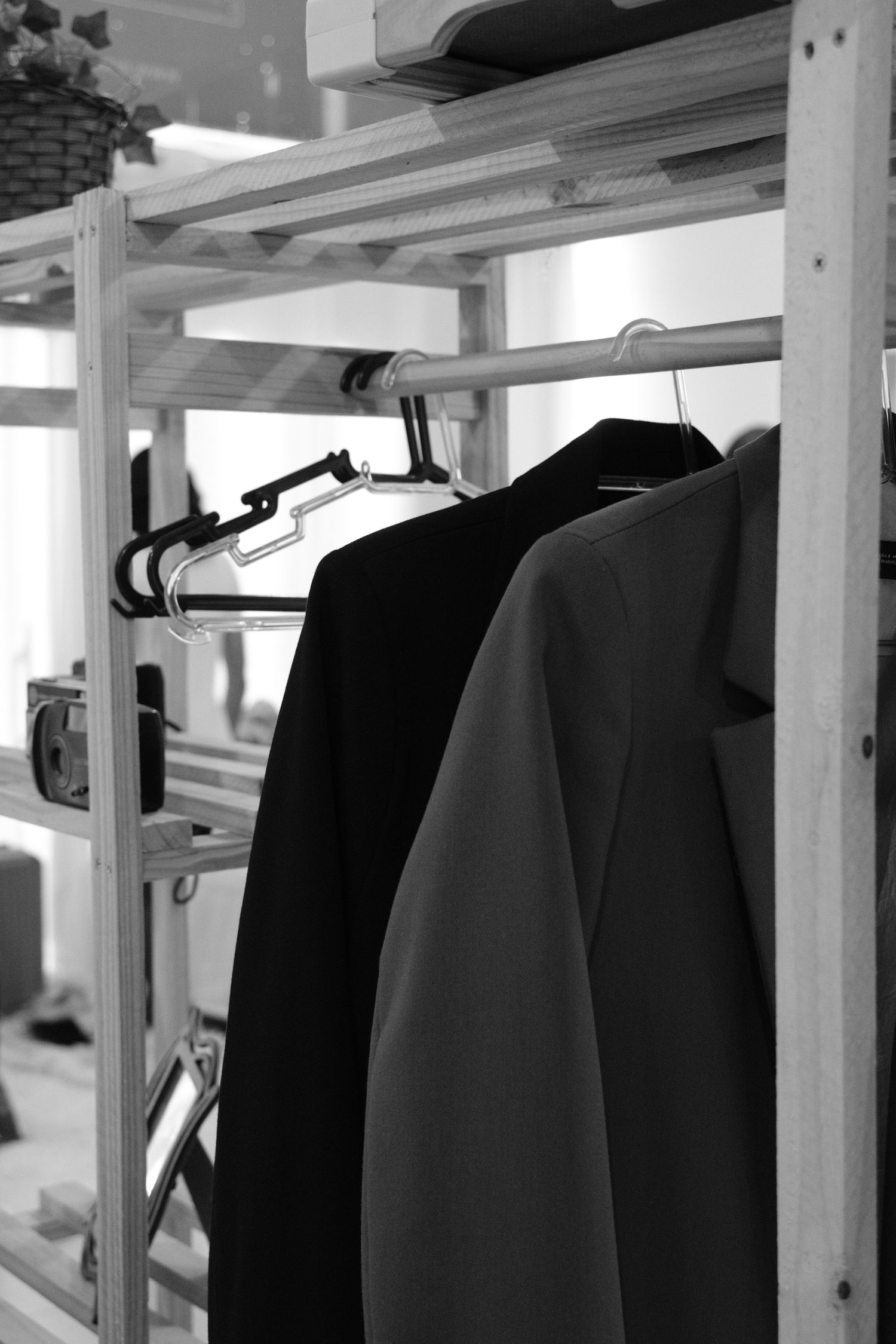 Monochrome photo of clothing on a wooden rack indoors adding style to an organized space.