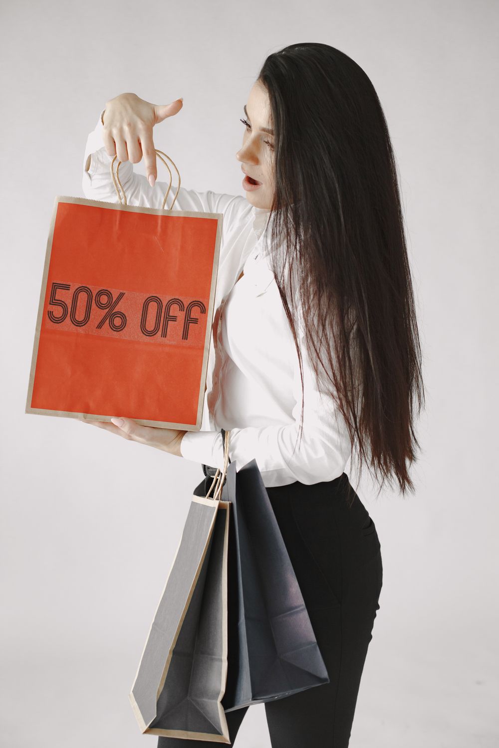 Woman in white blouse holding a "50% off" shopping bag, studio shot.