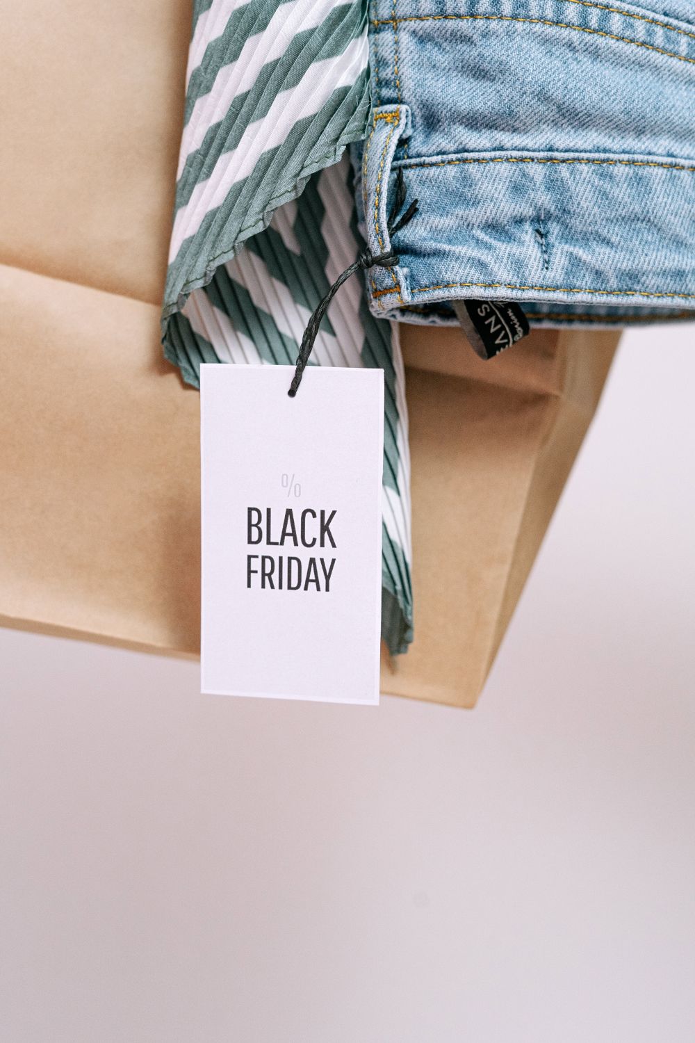 A Black Friday sale tag on a paper bag with denim clothing, symbolizing shopping discounts.