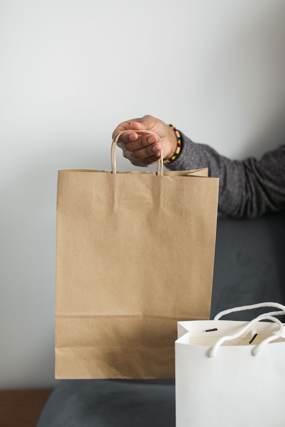 Close-up of a hand holding a brown paper shopping bag, emphasizing eco-friendly retail packaging.