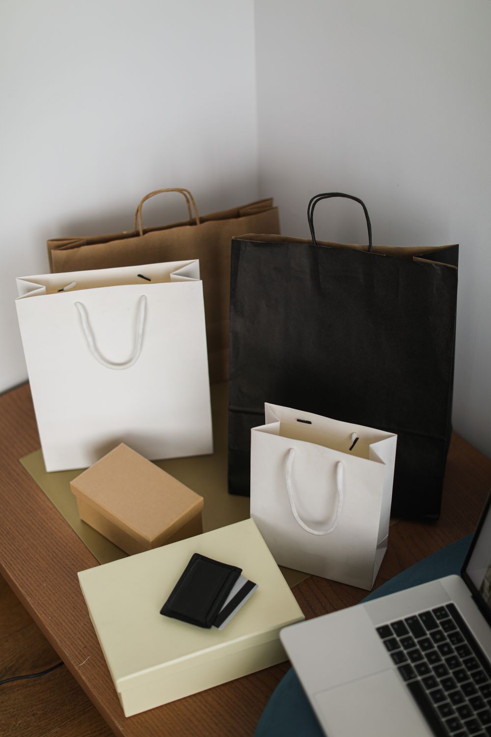 Arranged shopping bags and laptop on a wooden table, representing online shopping.