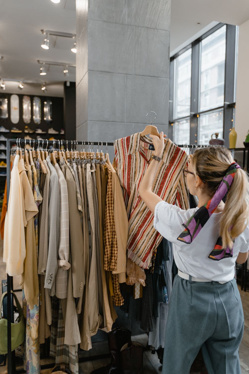 A woman browses clothes on a rack inside a stylish fashion boutique.