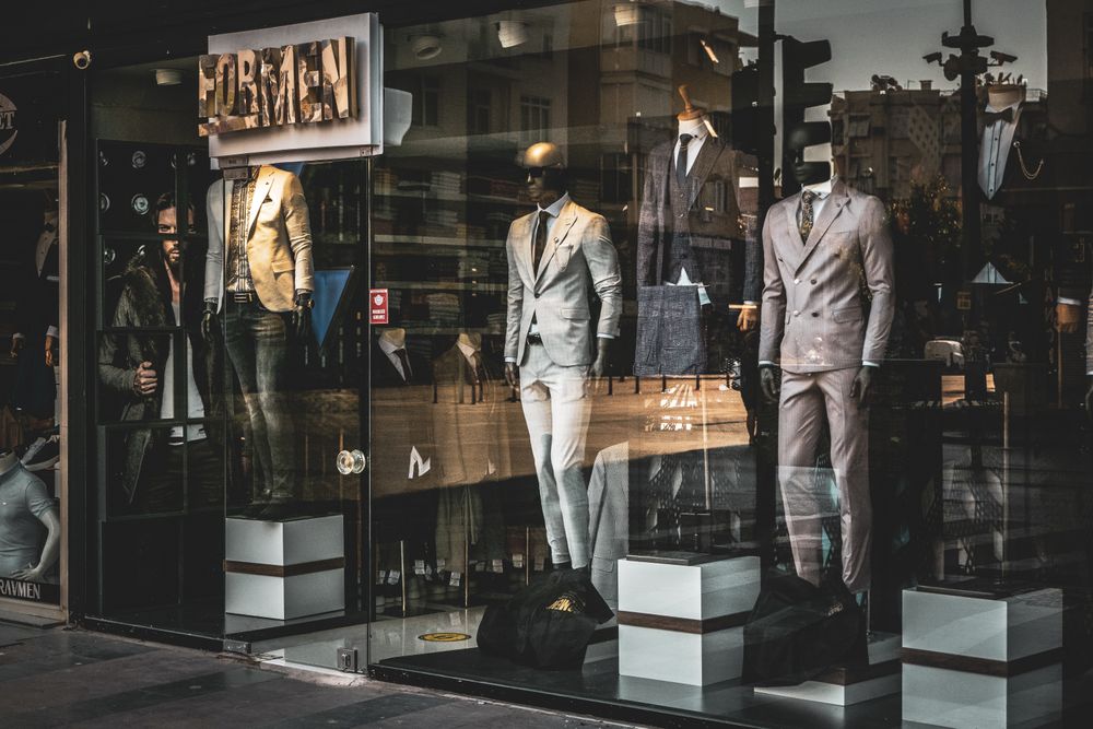 Stylish men's suits on mannequins in a boutique window display. Perfect for fashion and retail themes.
