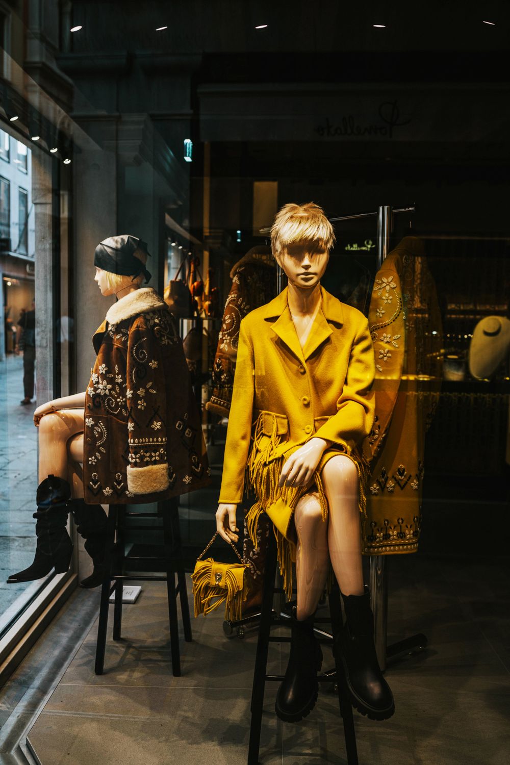 Modern fashion window display with stylish mannequins in urban setting, showcasing fall trends.