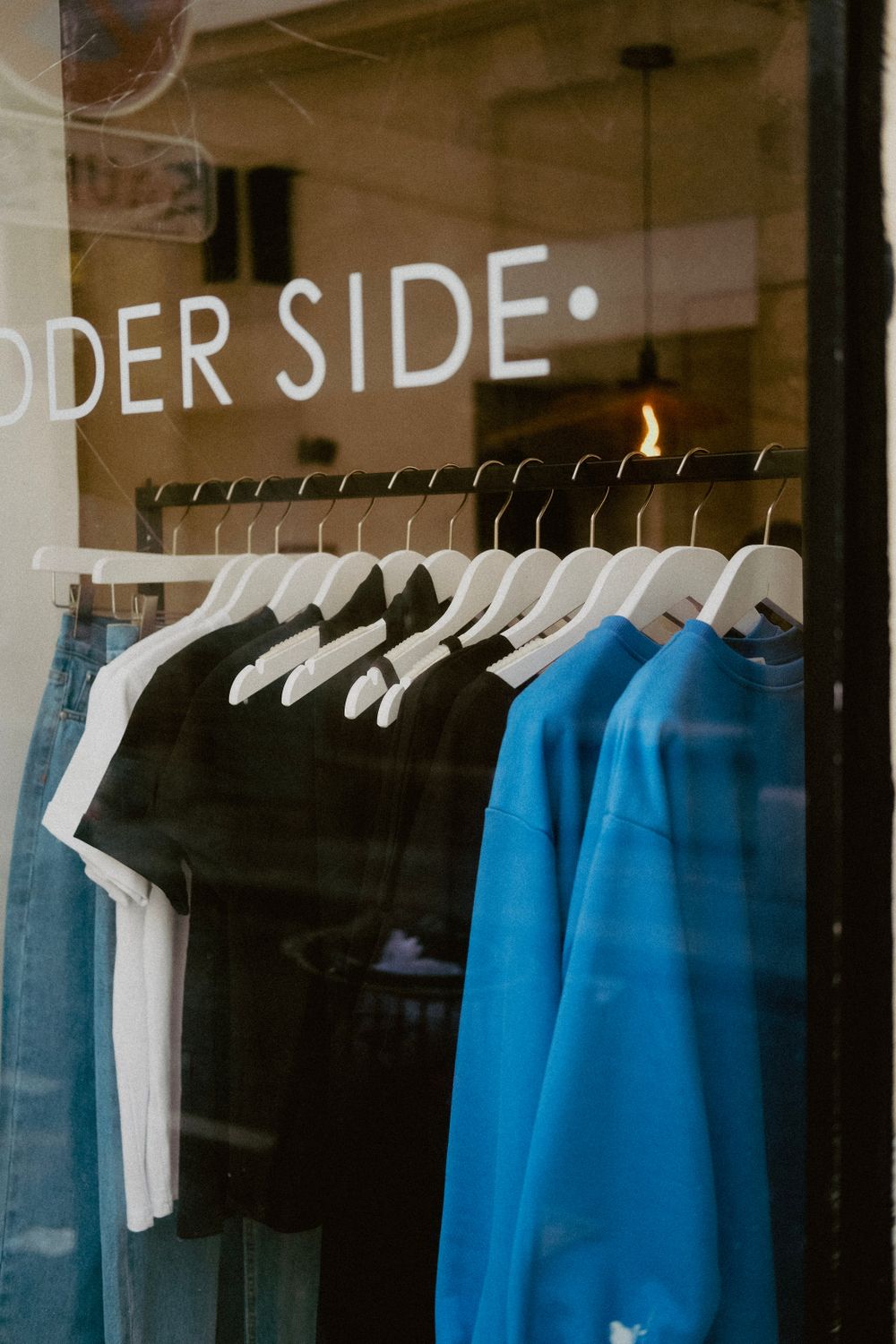 Stylish shirts and jeans hanging in a clothing store window, offering urban fashion.