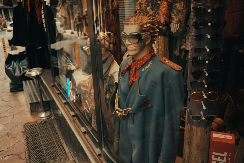 A mannequin with a unique outfit displayed in a vintage clothing store window.