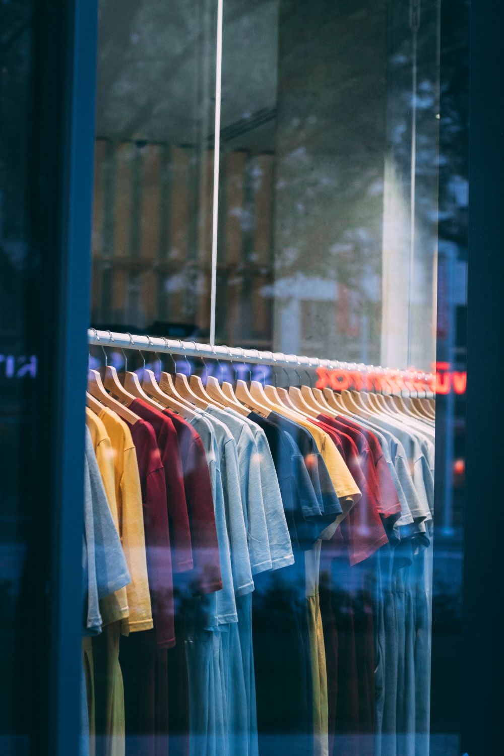 Colorful t-shirts hanging in a store window, showcasing a vibrant display.