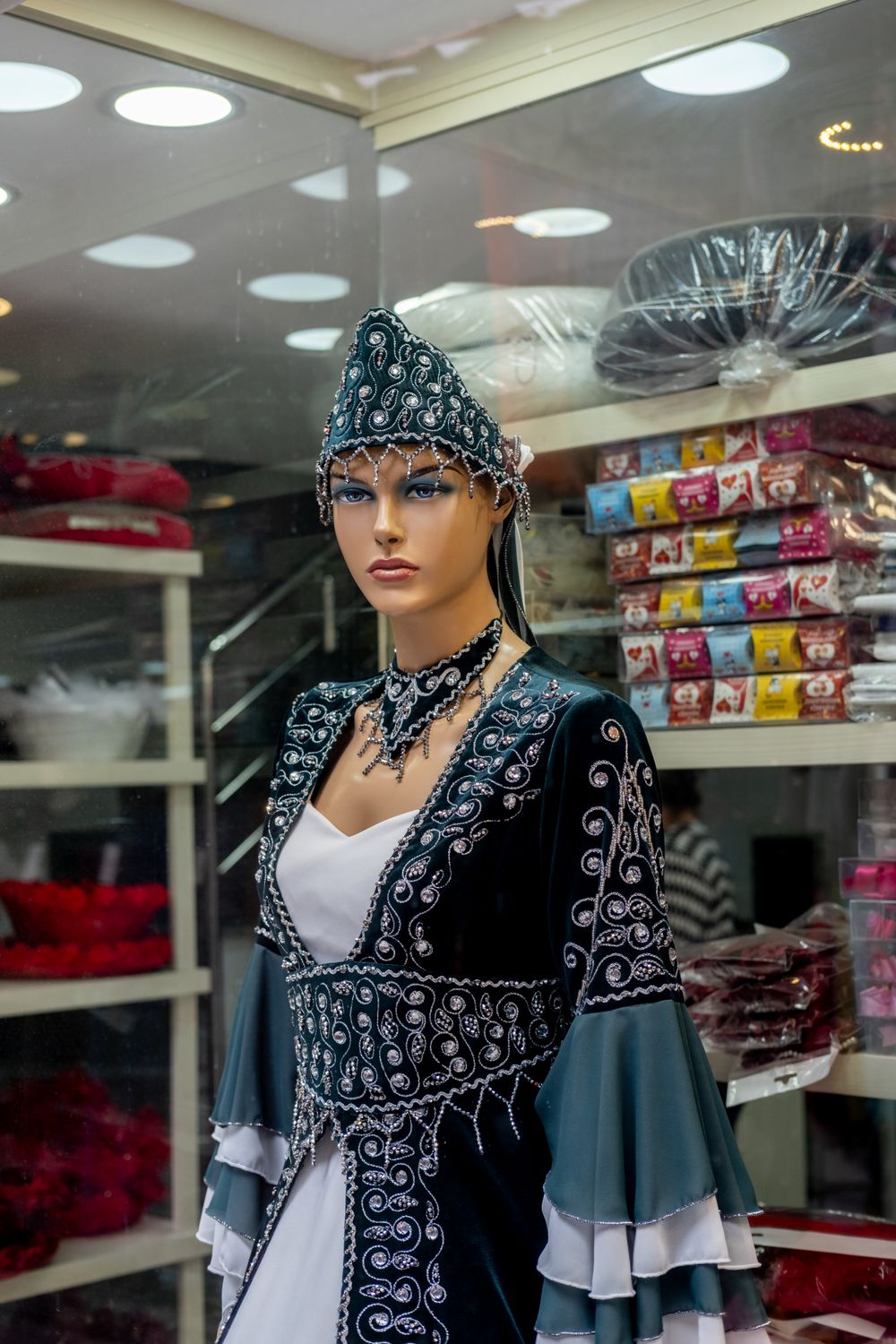 Mannequin displaying ornate traditional garment in a shop setting.