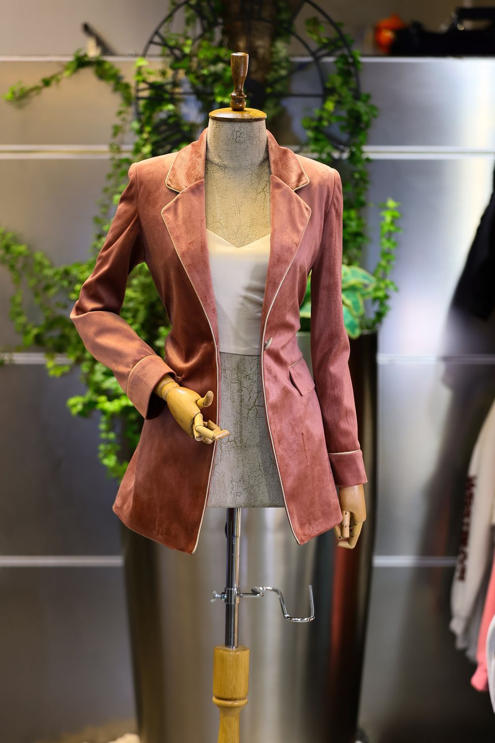 Stylish pink blazer displayed on mannequin in elegant fashion store setting.