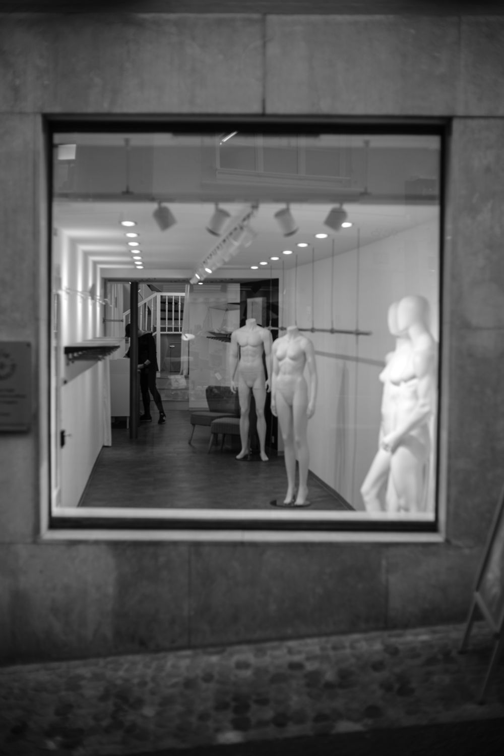 Minimalist black and white storefront featuring mannequins in a modern retail window display.