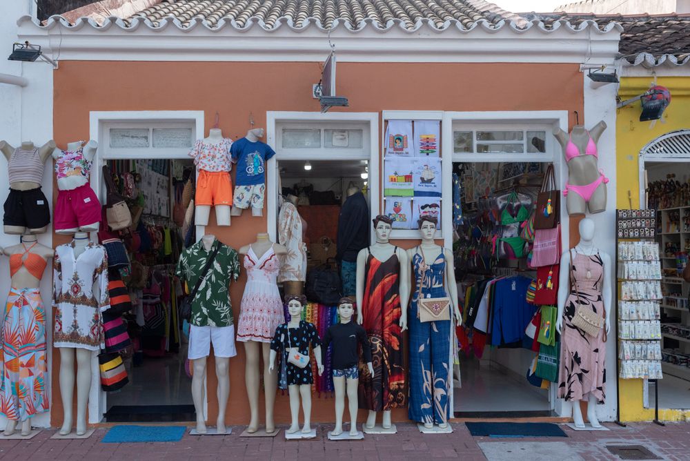 Street view of a vibrant clothing store display in Porto Seguro, Brazil featuring mannequins with summer outfits.