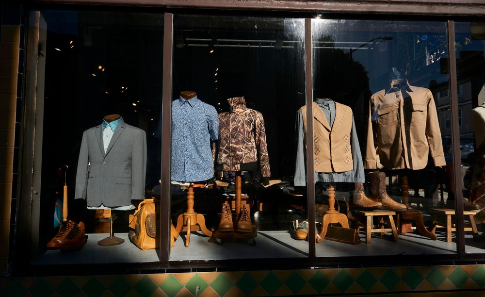 Elegant menswear display in San Francisco store window featuring suits and casual shirts.