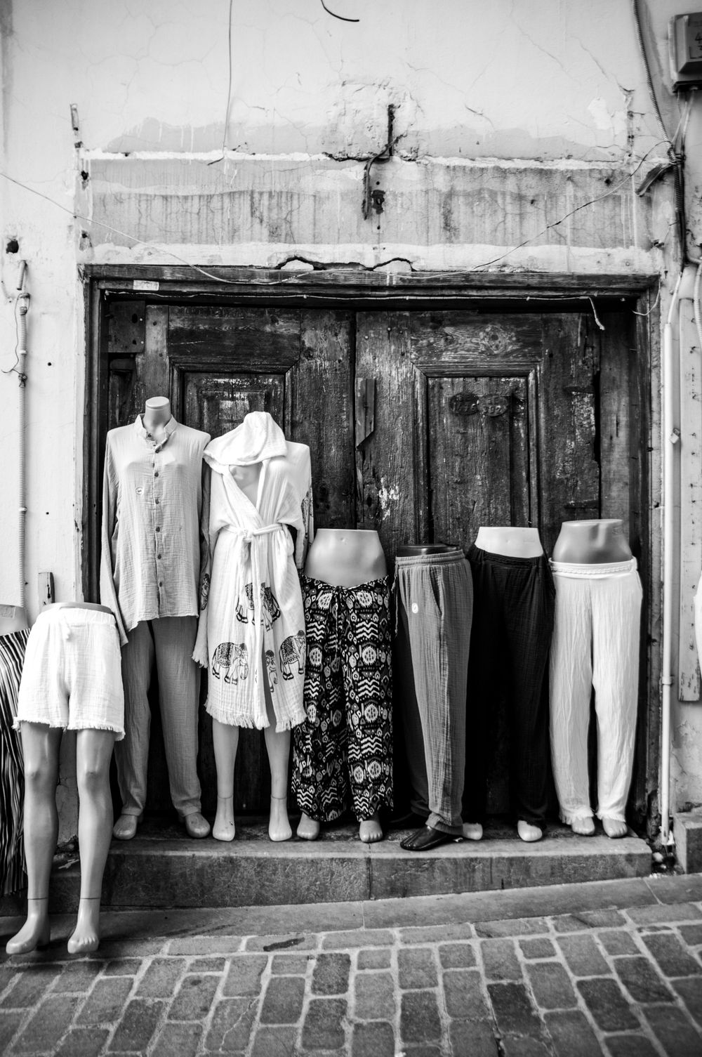 A row of mannequins dressed in casual apparel stand against a rustic wooden background.