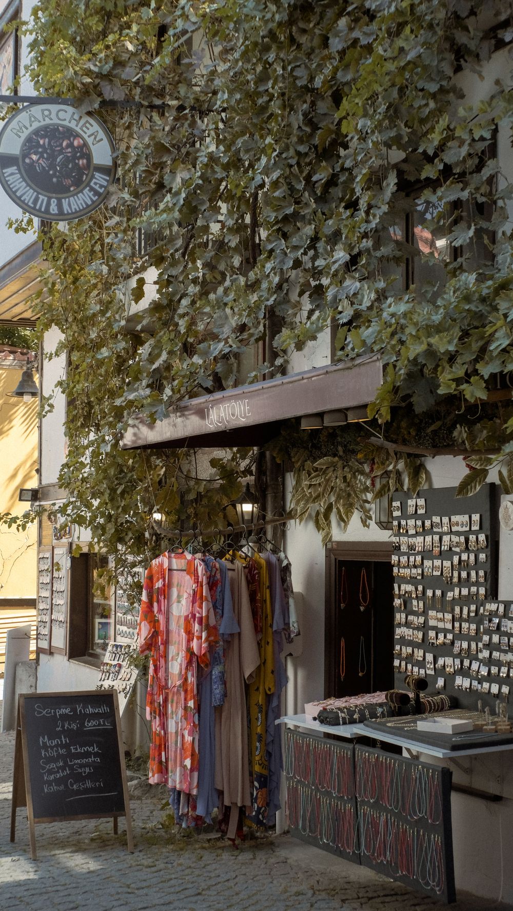 Charming street view of a boutique with an ivy-covered facade and clothes display.
