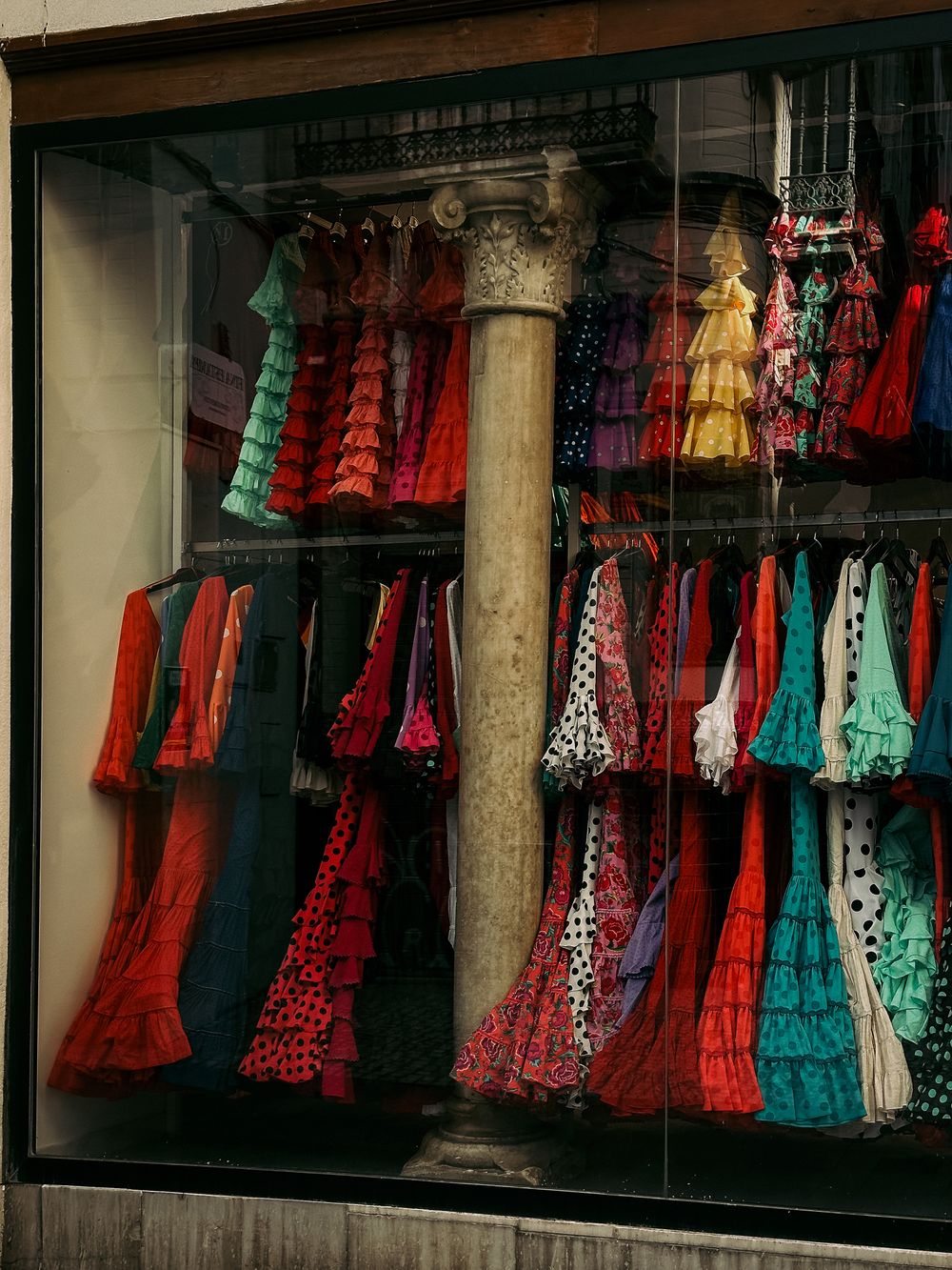 Vibrant display of traditional flamenco dresses in a Seville shop window.
