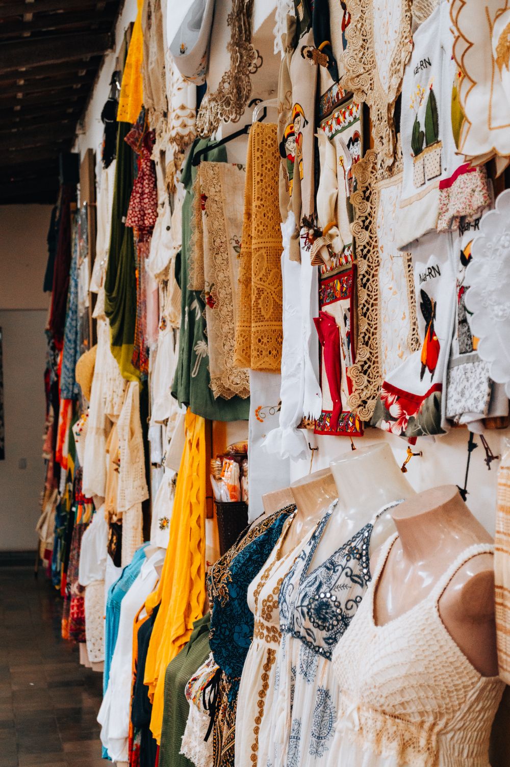 Vibrant display of traditional clothing and textiles in a market in Natal, Brazil.