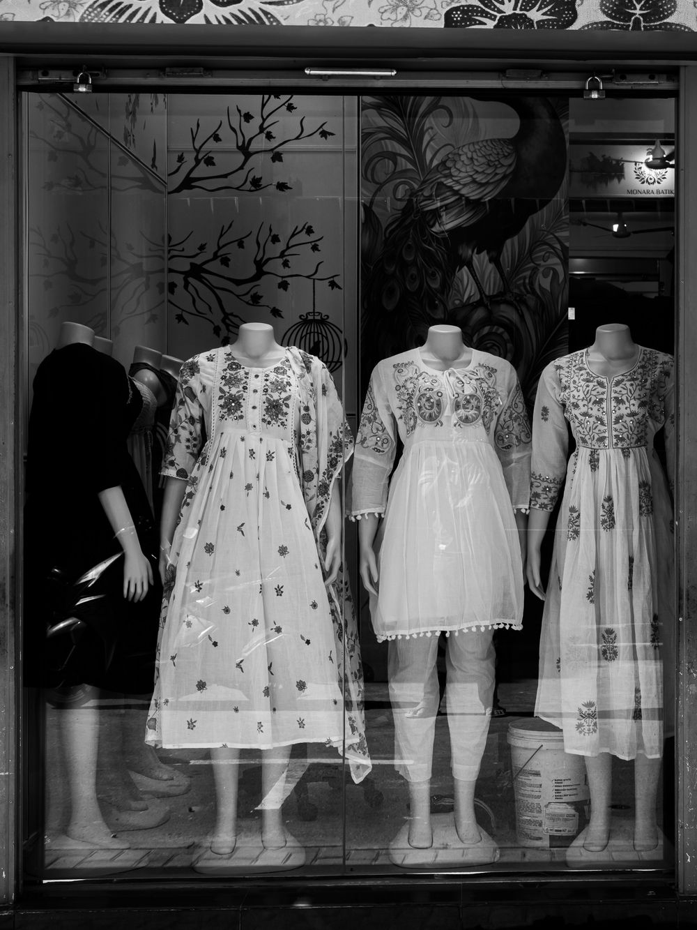Monochrome image of mannequins displaying intricate traditional dresses in a Colombo storefront.