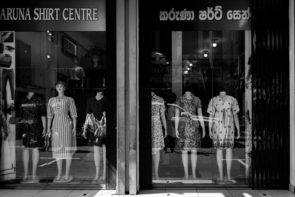 A storefront in Colombo, Sri Lanka featuring mannequins in various dresses seen through glass.