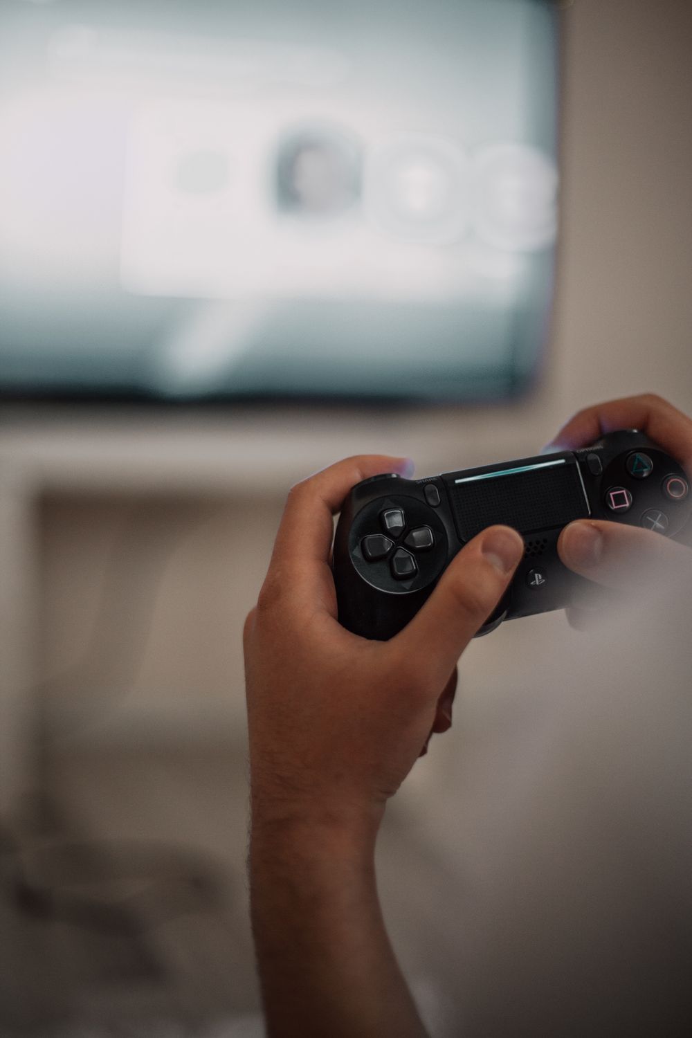 Person holding a game controller while playing in front of a TV screen, focused and interactive gaming moment.
