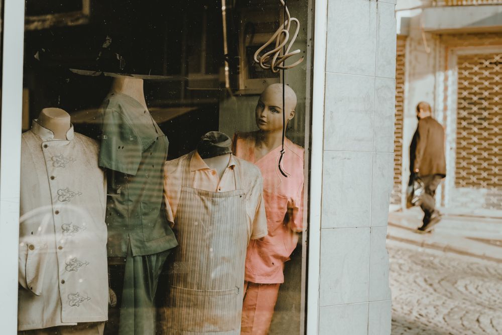 A shop window with mannequins displaying vintage clothing under a warm light.